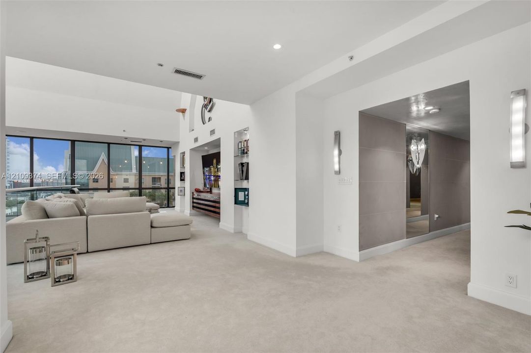 Interior space featuring expansive floor-to-ceiling windows, recessed lighting, built-in wall shelving, and wall-mounted light fixtures