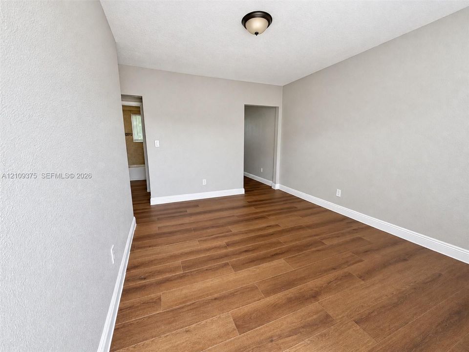 Neutral-toned interior space featuring wood-finish flooring and a central flush-mount ceiling light fixture