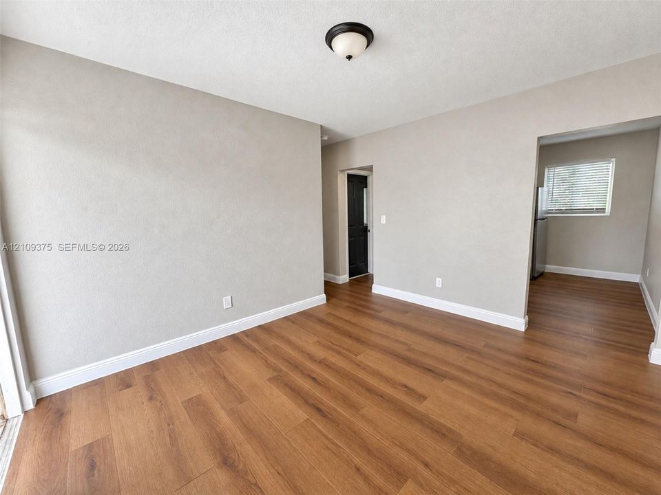 Neutral-toned interior space featuring wood-finish flooring, a flush-mount ceiling light fixture, and a solid-core interior door