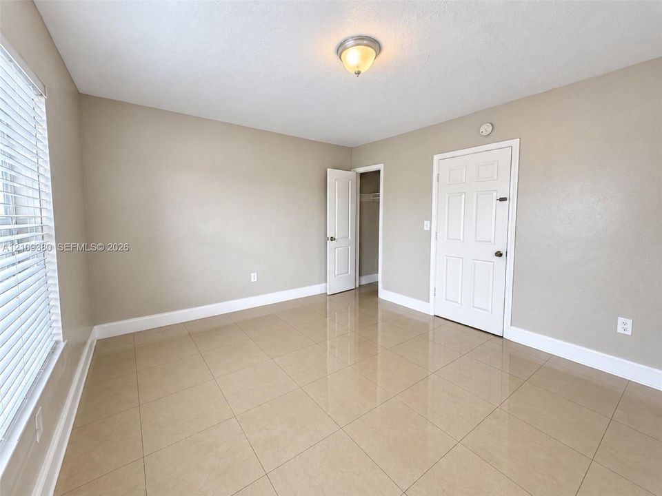Neutral-toned interior featuring large-format ceramic tile flooring, six-panel interior doors, and a flush-mount ceiling light fixture