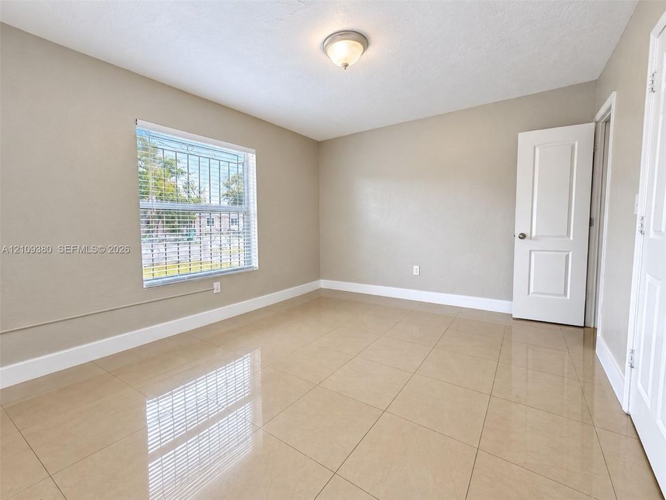 Neutral-toned walls, large-format tile flooring, single-panel interior door, and a flush-mount ceiling light fixture