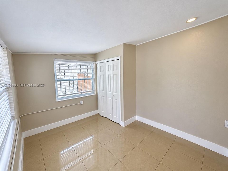 Polished tile flooring, recessed ceiling lighting, and built-in closet with folding doors