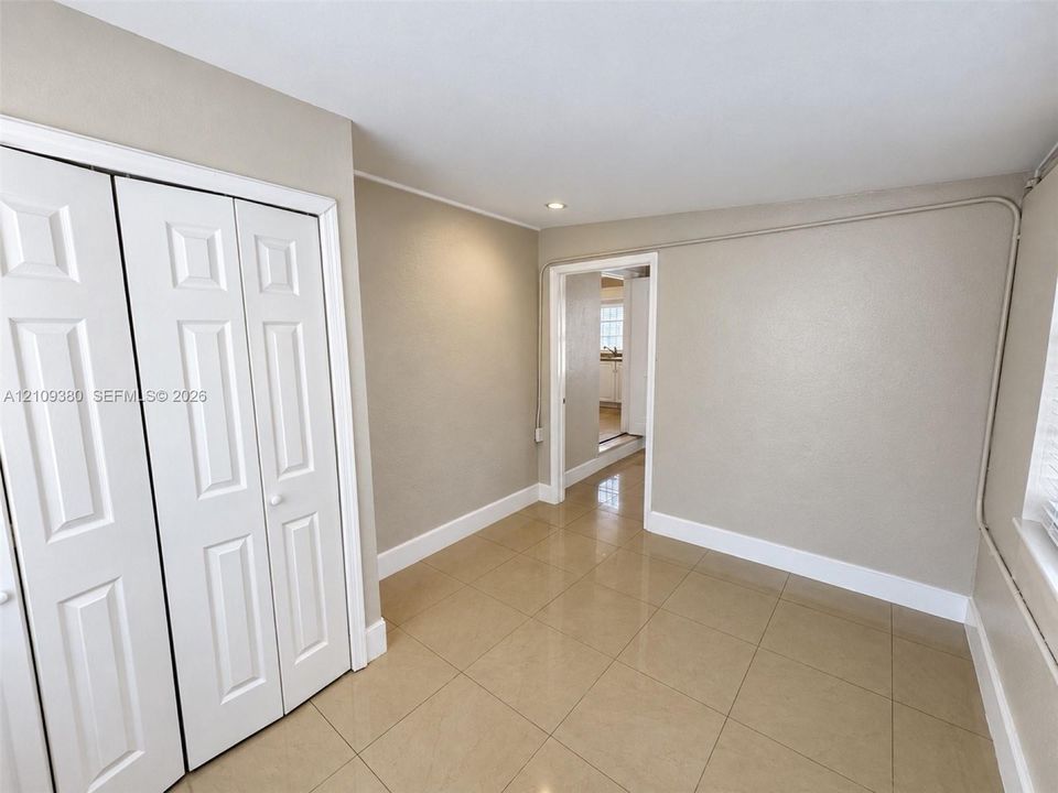 Neutral-toned interior space featuring large-format ceramic tile flooring and double-panel white closet doors