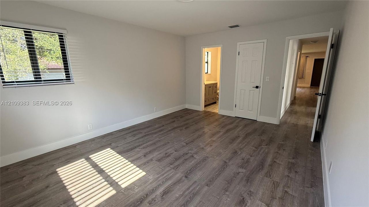 Neutral-toned interior featuring wood-finish flooring, a single-hung window, and a white six-panel interior door