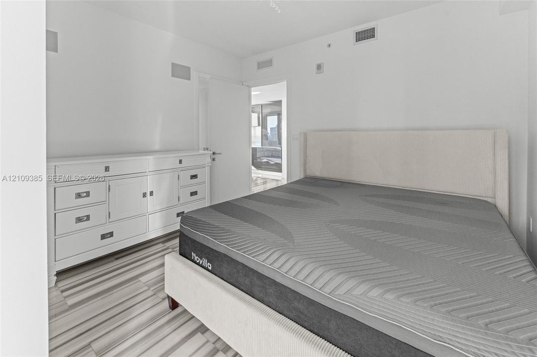 Walk-in storage space featuring wood-finish open shelving, built-in lower drawers, and tile flooring