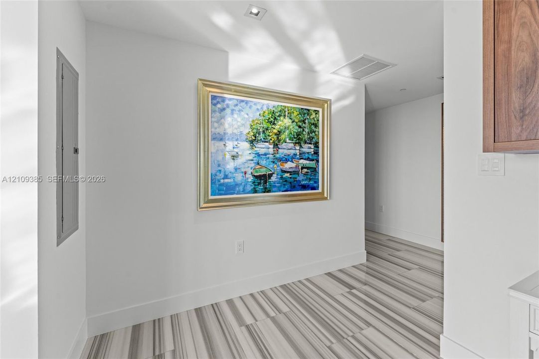 Glossy charcoal cabinetry, wood-finish wall-mounted cabinetry, and large-format tile flooring
