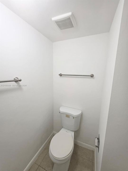 Two brushed nickel wall-mounted towel bars and a standard-height porcelain toilet