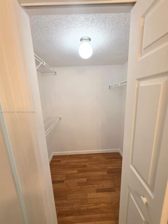 Interior space featuring neutral tile flooring, sliding glass door with vertical blinds, brushed metal ceiling fan, white louvered-door closet, and an overhead bowl-style pendant light