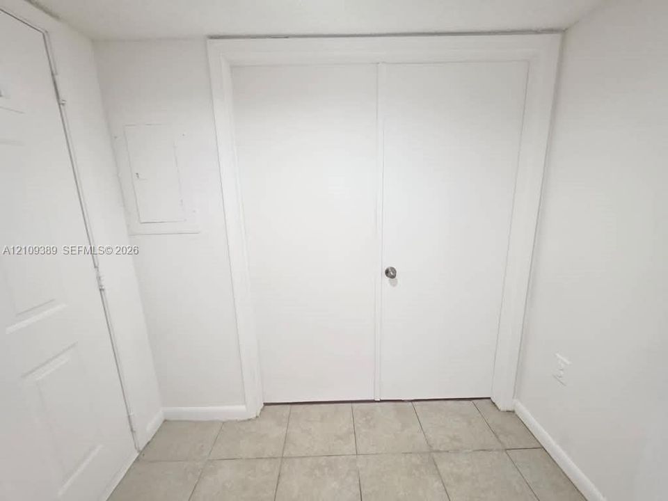 Dark wood-finish cabinetry, stone-surface countertop, integrated vanity sink, large wall-mounted mirror, and tile flooring