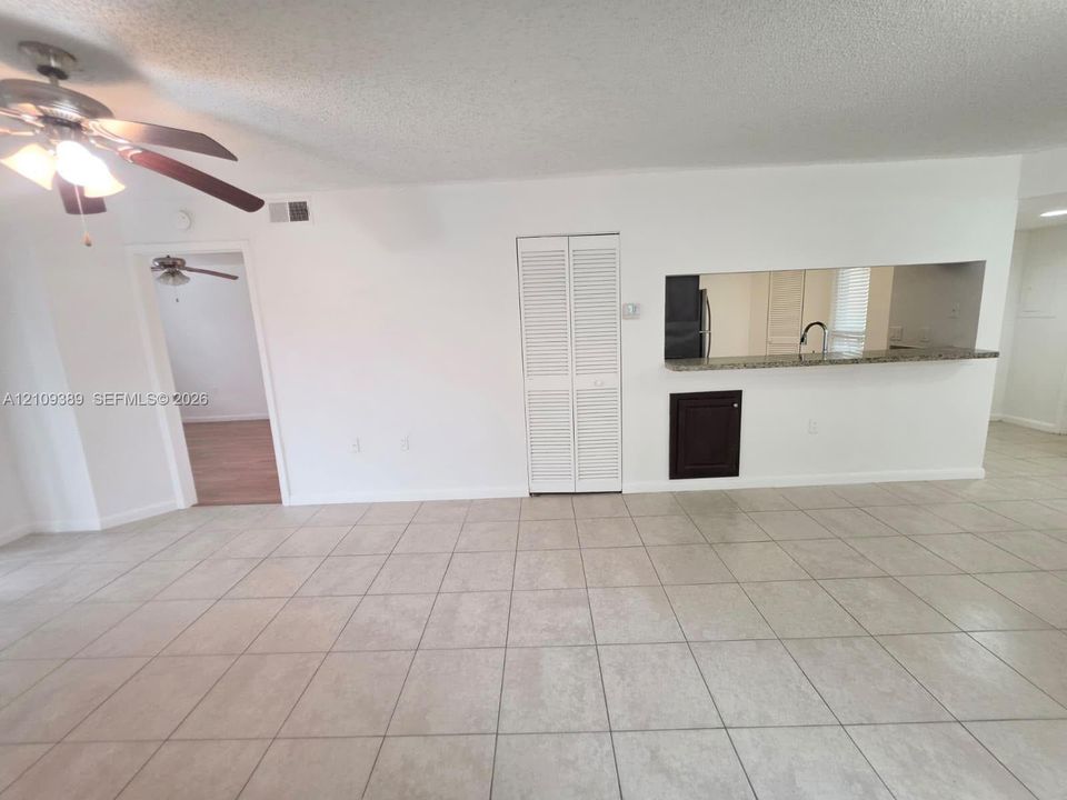 Kitchen featuring dark-toned cabinetry, stainless steel appliances, ceramic tile flooring, and a dedicated laundry alcove with a stackable washer and dryer unit
