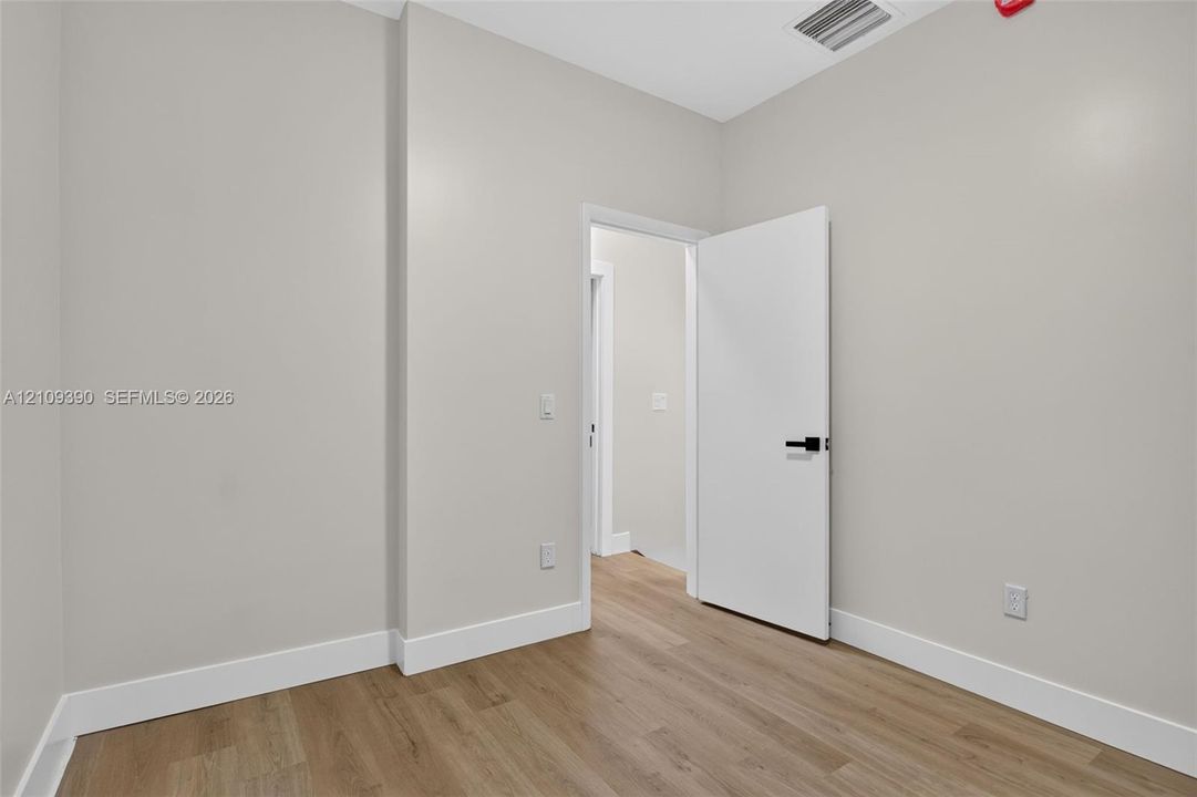 Neutral-toned walls paired with wood-finish flooring and a white interior door featuring matte black hardware