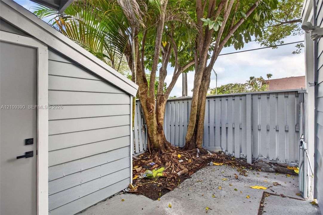 Exterior utility space featuring horizontal lap siding, concrete flooring, and a privacy-style fenced enclosure