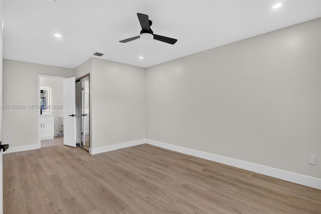 Neutral-toned interior featuring wood-finish flooring, recessed lighting, and a matte black ceiling fan