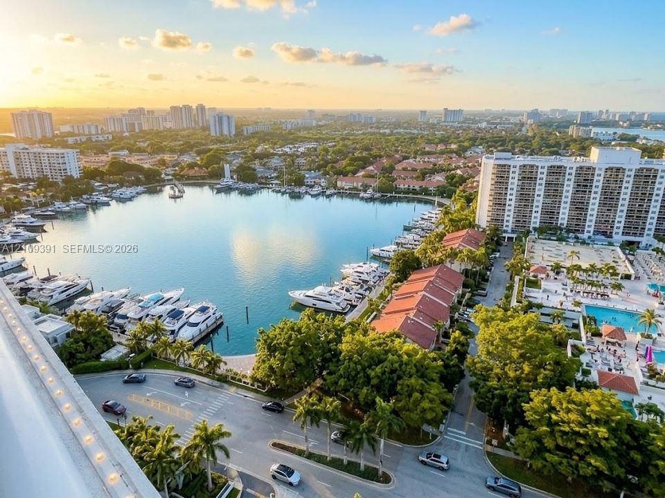 Aerial perspective of a coastal community featuring a deep-water marina, multiple high-rise structures, a private swimming pool, and established tropical landscaping