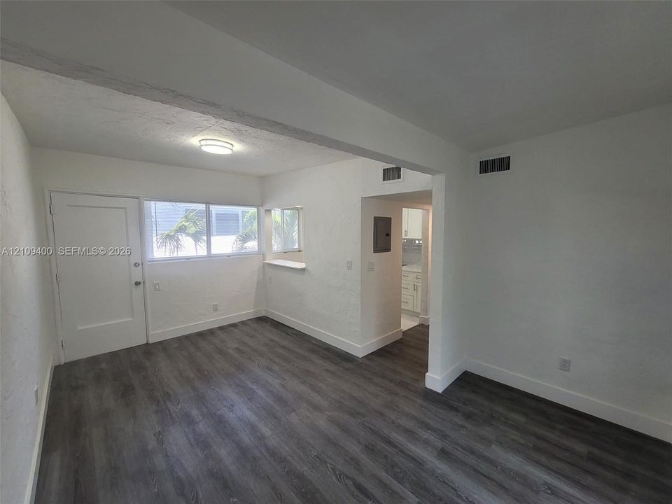 Interior space featuring wood-finish flooring, textured walls, a multi-pane window with a built-in sill, and a recessed ceiling light fixture