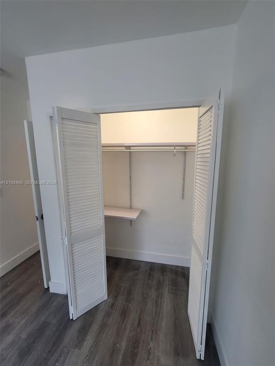 Closet featuring white louvered bifold doors, adjustable shelving tracks, and an upper shelf