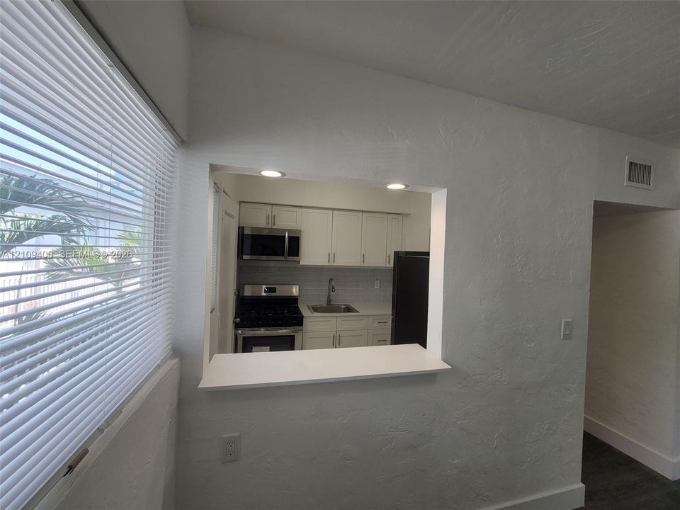 Kitchen pass-through window with a white countertop, recessed lighting, white shaker-style cabinetry, stainless steel appliances, and tile backsplash