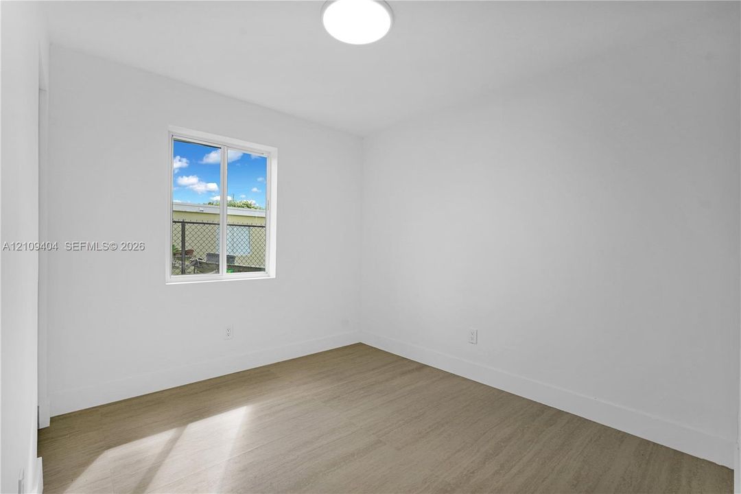 Interior space featuring white walls, wood-finish flooring, and a flush-mount overhead light fixture