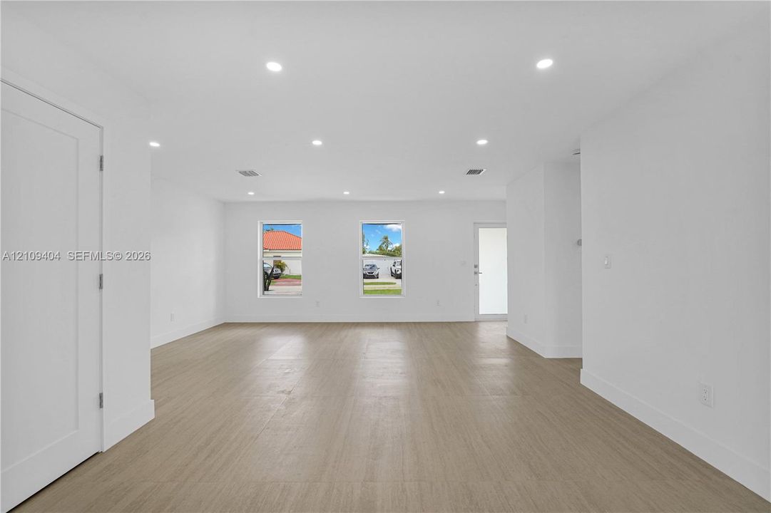 Open-concept interior featuring light wood-finish flooring, recessed lighting, and crisp white wall finishes