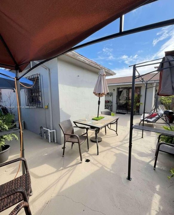 Outdoor patio featuring concrete surfacing, stucco exterior walls, and metal window security grilles