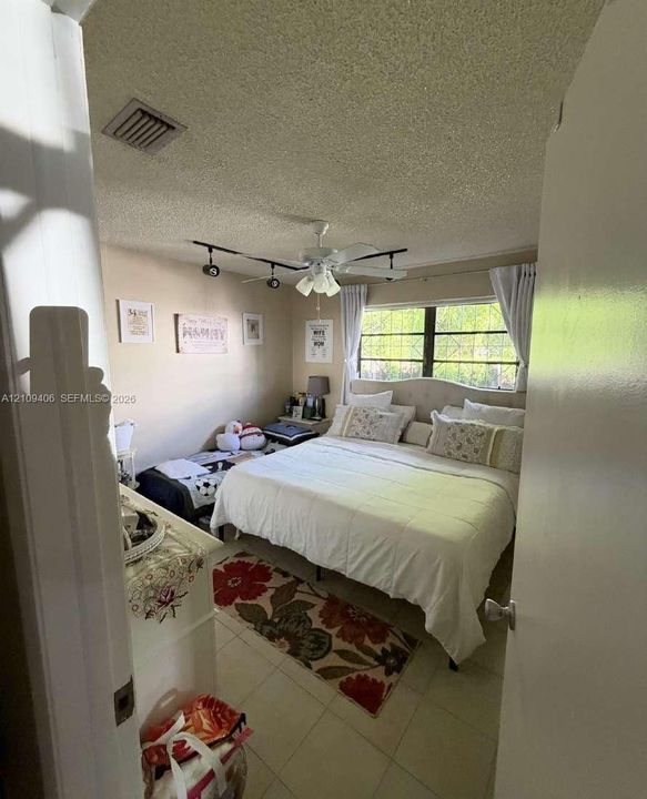 Interior room featuring a large multi-pane window, ceiling fan with integrated track lighting, and tile flooring