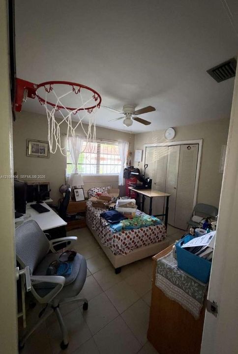 Neutral-toned room featuring tile flooring, a ceiling fan, and double-door closet storage