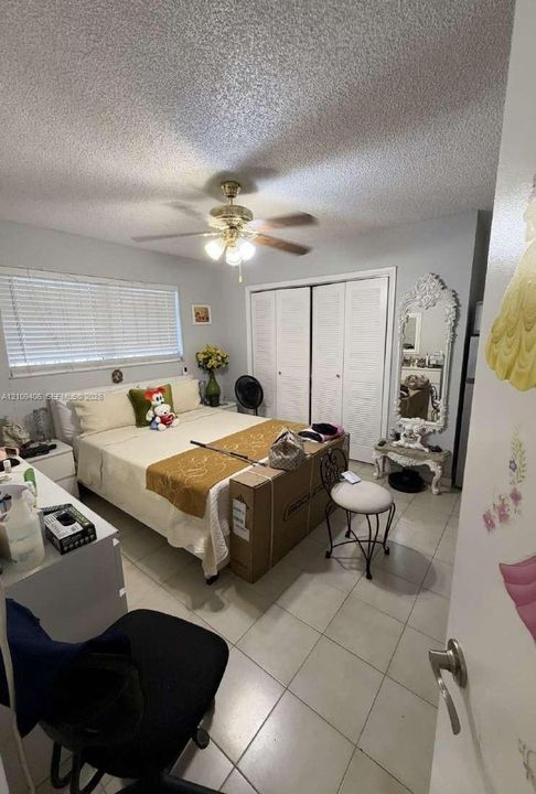 Ceramic tile flooring, multi-panel closet doors, and central ceiling fan with integrated lighting