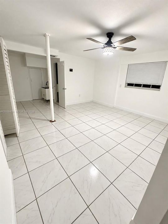 Interior space featuring white stone-finish tile flooring, ceiling fan with integrated lighting, and louvered closet doors