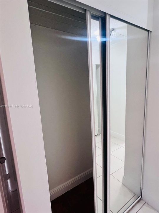 Full-height sliding mirrored closet doors with a white metal frame
