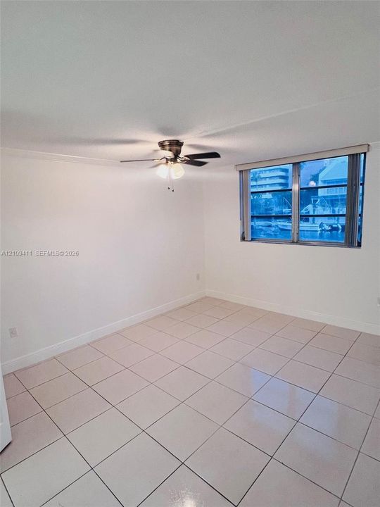 Neutral-toned tile flooring, ceiling fan with integrated lighting, and metal-framed window