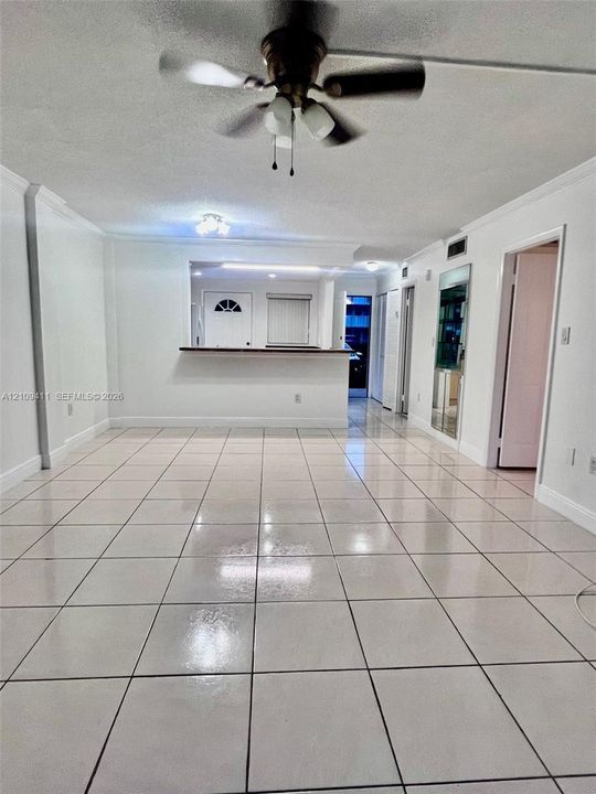 Interior space featuring large-format ceramic tile flooring, a pass-through service counter, and a ceiling fan with integrated lighting