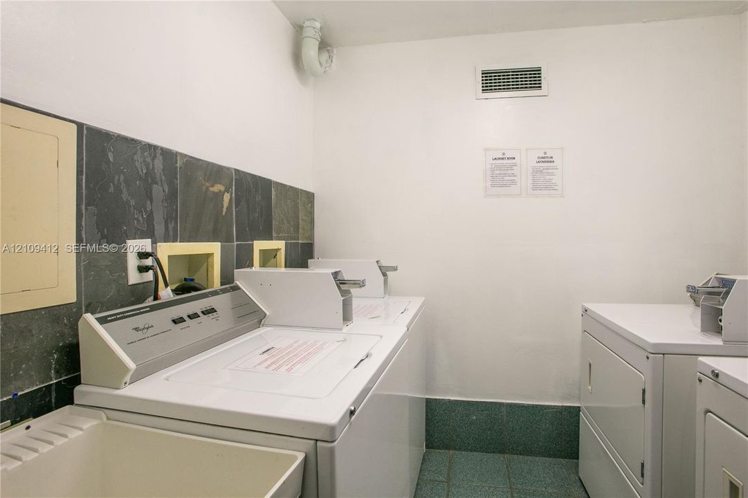 Laundry area featuring tile flooring, stone wall backsplash, and a utility sink