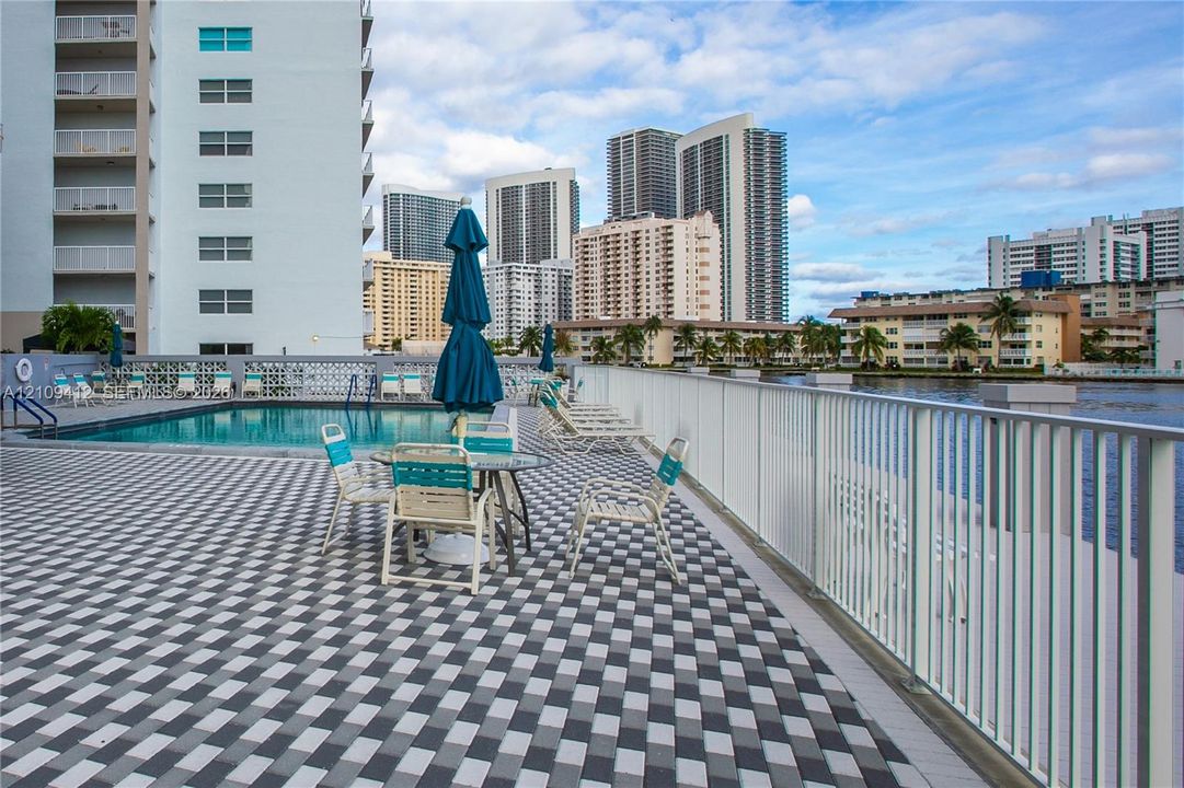 Pool deck featuring patterned paver surfacing, rectangular swimming pool, and metal perimeter railing