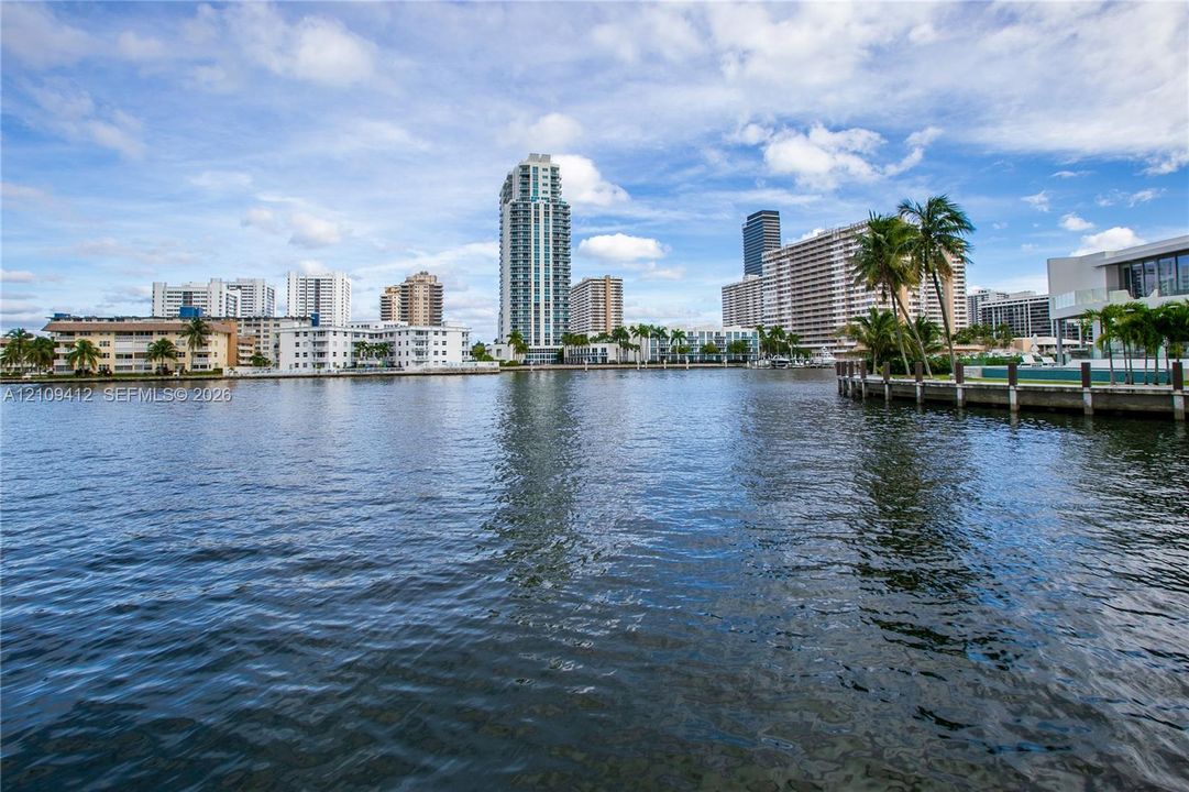 Waterfront location featuring a concrete bulkhead, paved grounds, and palm tree landscaping