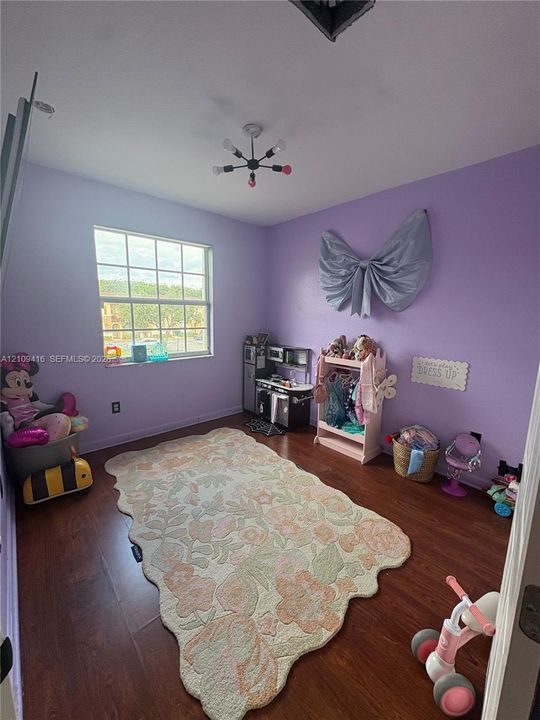 Room featuring wood-finish flooring, a multi-light modern ceiling fixture, and a single-hung window with a grid pattern