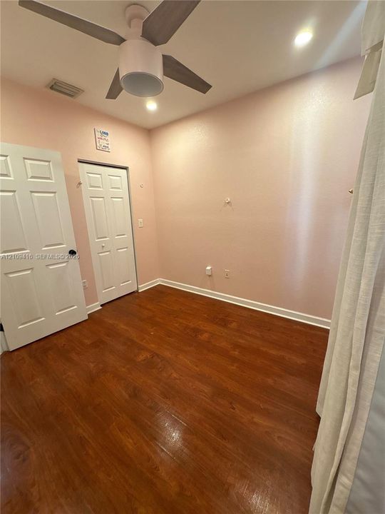 Wood-finish flooring, ceiling fan with integrated lighting, recessed lighting, and two interior doors with paneled detailing