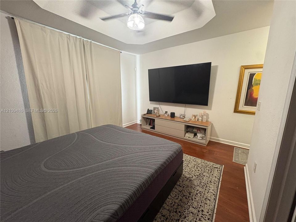 Tray ceiling, ceiling fan with integrated lighting, and wood-finish flooring