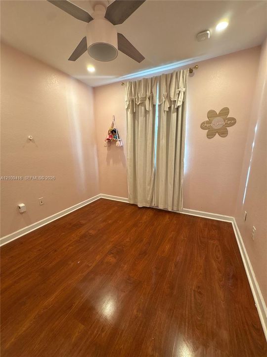 Wood-finish flooring, ceiling fan with integrated lighting, and neutral wall paint