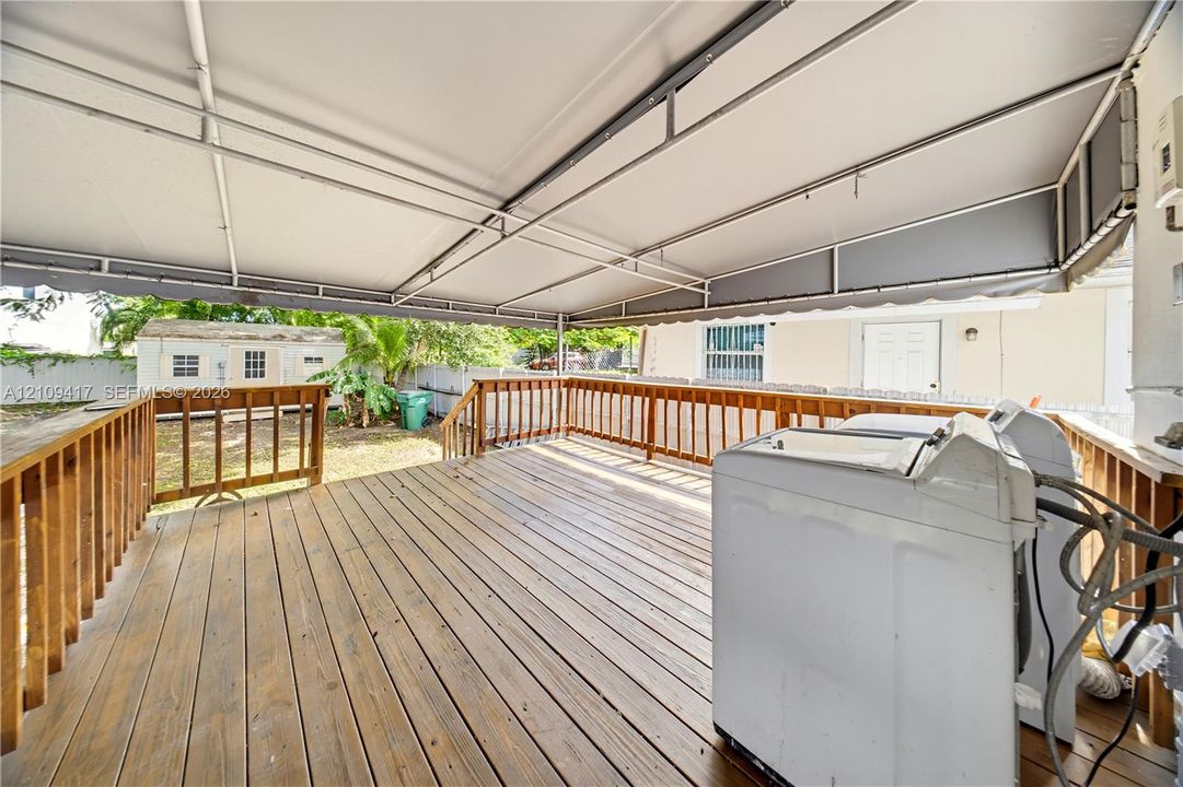 Covered wooden deck featuring a metal-framed awning and a perimeter railing
