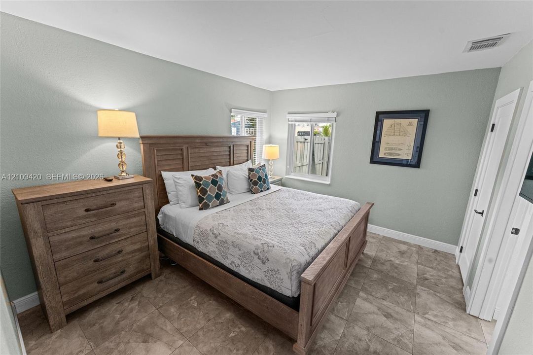 Neutral-toned wall finish, large-format tile flooring, and dual-pane windows with horizontal blinds