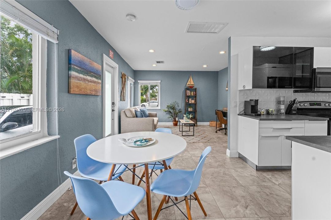 Kitchen featuring white cabinetry, dark countertops, a textured tile backsplash, and tile flooring, enhanced by recessed lighting