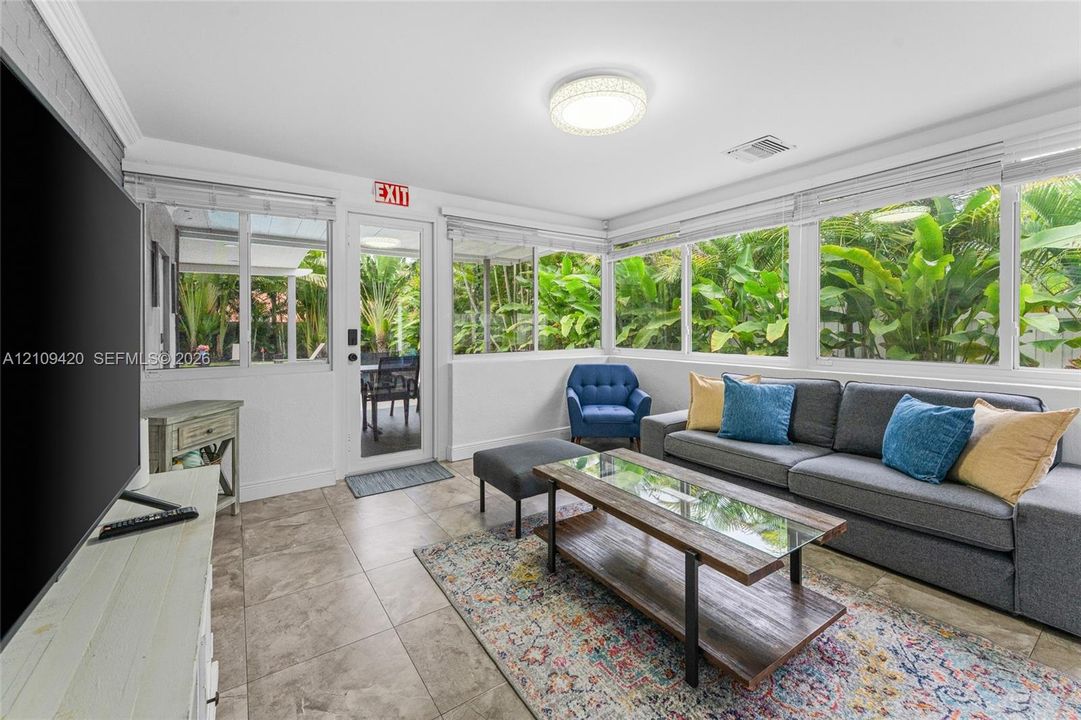 Sunroom featuring expansive windows, tile flooring, crown molding, and a flush-mount light fixture