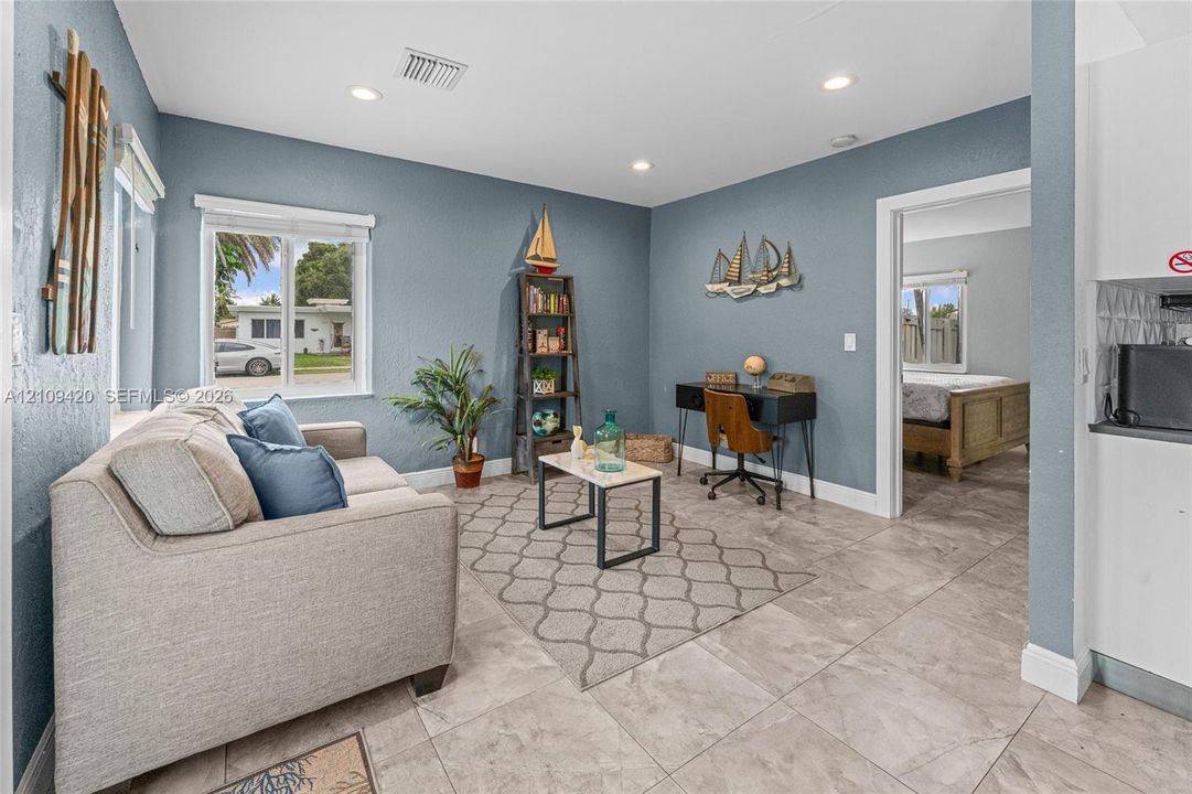 Living area featuring neutral-toned tile flooring, recessed lighting, and a window providing natural light