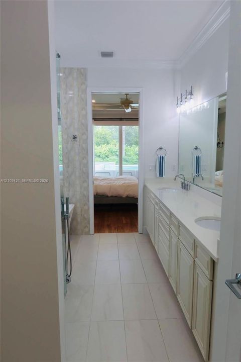 Bathroom featuring dual-sink vanity with light-tone cabinetry, quartz countertop, full-width wall mirror, and large-format tile flooring