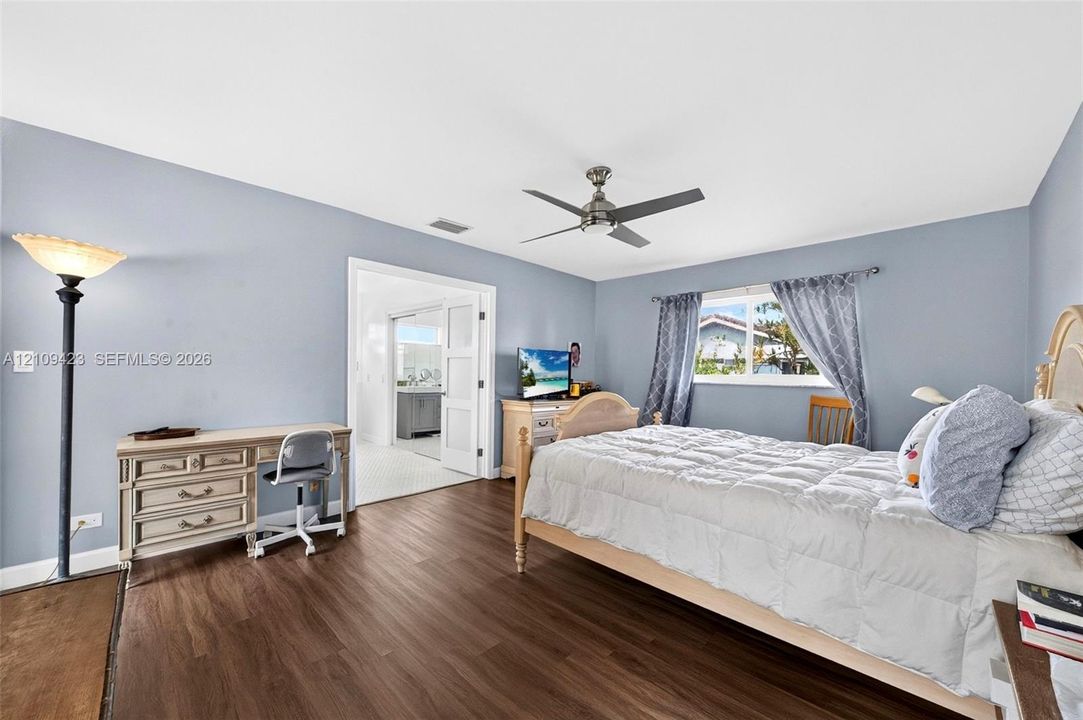 Wood-finish flooring, neutral-toned wall paint, a multi-speed ceiling fan, and double-panel sliding doors