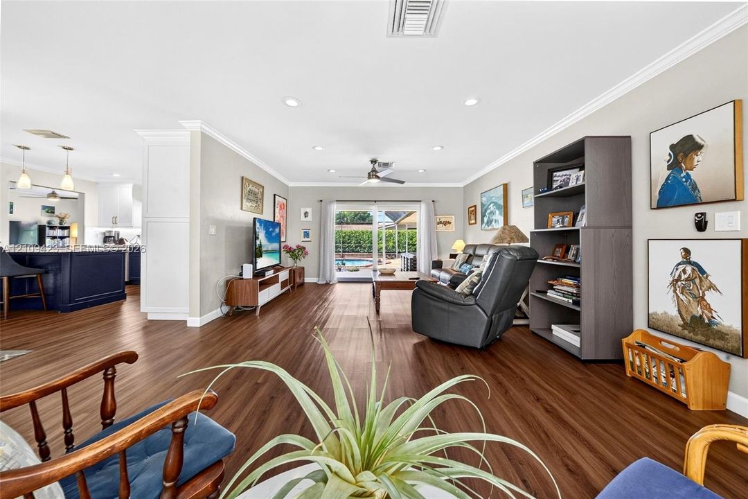 Open-concept space featuring wood-finish flooring, recessed lighting, crown molding, and sliding glass doors with exterior access