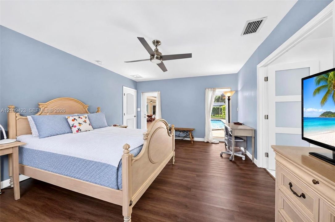 Wood-finish flooring, brushed metal ceiling fan, and multi-panel interior doors