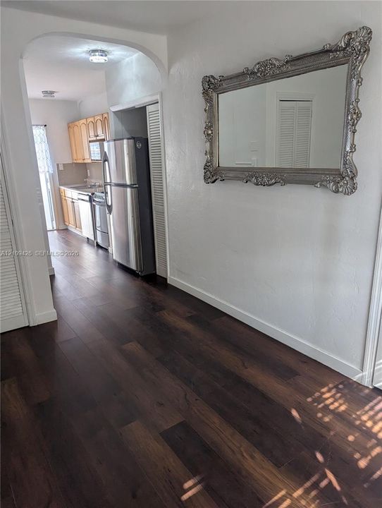 Interior featuring dark wood-finish flooring, an arched entryway, louvered closet doors, and recessed lighting
