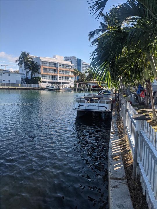 Waterfront property featuring a concrete seawall, picket fencing, and mature palm trees