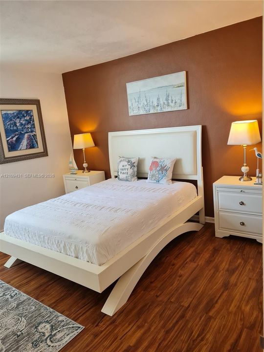 Wood-finish flooring throughout the room with a bold accent wall
